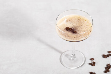 martini and espresso cocktail in a glass on a grey background, hard light, shadows, horizontal, space for text