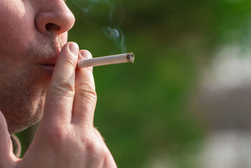 Cropped close up man smoking cigarette outdoors