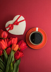 Bouquet of red  tulips and gift heart box, coffee cup arrangement with a lot of copy space for text. Spring mood concept. Greeting card for Birthday, Woman, Mother's Day, Wedding, Valentines day.