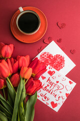 morning coffee and a bouquet of red tulips on a bright red background. View from above.Copy space for text. The concept of holidays.