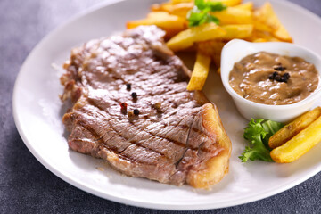 grilled beef steak with french fries and pepper sauce