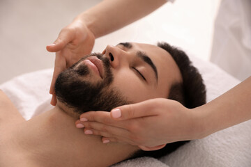 Obraz na płótnie Canvas Young man receiving facial massage in beauty salon, closeup