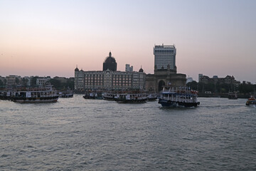 Taj Mahal hotel, Gateway of India and tourist boats in water of Arabian Sea on sunset in Mumbai, India