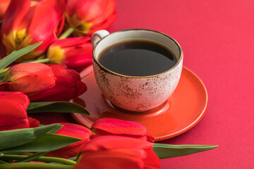 Fototapeta na wymiar Bouquet of red tulips and coffee cup arrangement with a lot of copy space for text. Spring mood concept. Greeting card for Birthday, Woman, Mother's Day, Wedding, Valentines day.