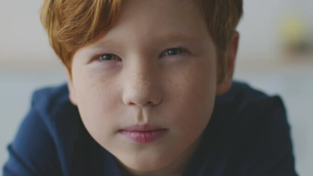 Kids eyesight problems. Little redhead boy with freckles squinting eyes, peering to camera, feeling troubles with vision