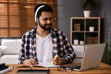 Young man watching webinar at table in room