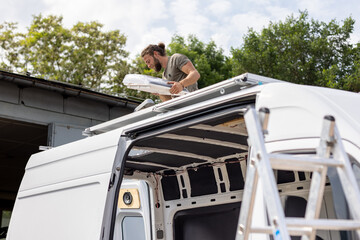 Man on the roof of a van installing a skylight