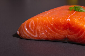 Fresh raw salmon or trout sea fish fillet on black stone background