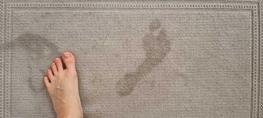 Female standing barefoot on the carpet. Wet footprint on the linen rug. Bathing signs. Hygiene procedure at home.