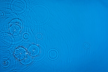 Transparent dark blue colored clear calm water surface texture with ripples, splashes and bubbles...