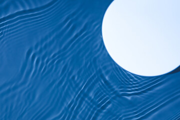 Empty white circle podium on transparent clear dark blue water texture with splashes and waves in...
