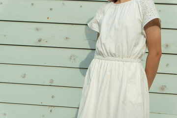Girl standing in front of a retro light blue wall. レトロな水色の壁の前に立つ女の子