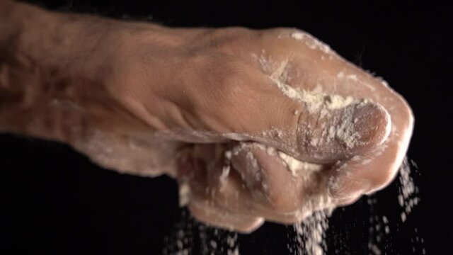 Pour Flour From a Man's Hand on a Black Background