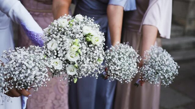 Bouquets of fresh twigs of gypsophila flowers. Holiday, the bride with her girlfriends holding bouquets of white flowers. In woman, a bunch of gypsophila and roses