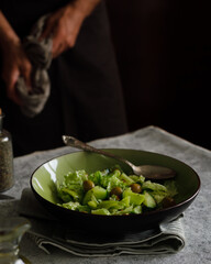 a man prepares a vegetable salad on a dark background. Dark photo style.