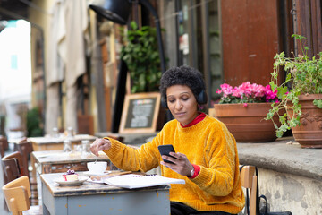 Italy, Tuscany, Pistoia, Woman sitting in outdoor cafe and using smart phone