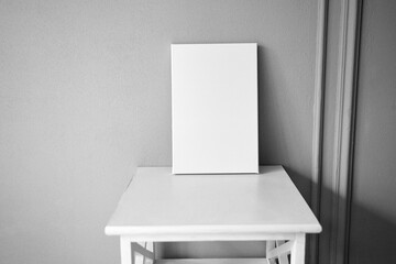White canvas mockup, blank picture on wooden table in interior with grey wall