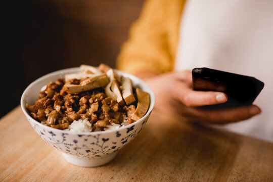 Lu Rou Fan dish near woman with smartphone