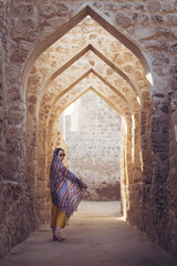 Woman walking on arched passage of stone building