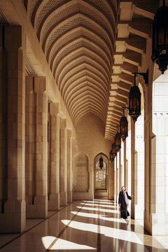 Woman walking in arched passage of mosque