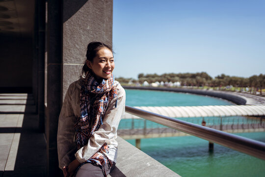 Smiling woman admiring picturesque scenery with city park and ba