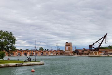 Naklejka premium Industrial shipyards (Arsenale di Venezia) in Italy, Venice. Loading cranes and docks. Cloudy, summer.