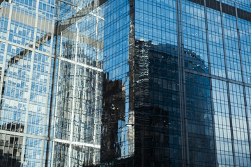 Business and finance concept. Exterior of a modern high-rise office building. Close-up of blue glass skyscraper, city reflection