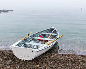 Traditional wooden rowboat sitting on a beach in fog with traditional wooden oars.  Shot in the...