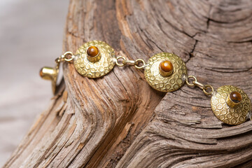 golden discs mineral stone brass bracelet with tyger eye on wooden background