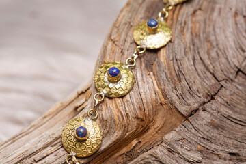 golden discs mineral stone brass bracelet with lapis lazuli on wooden background