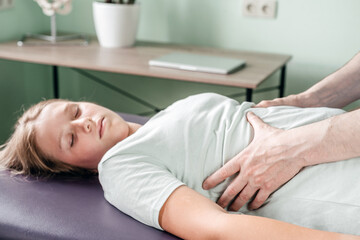 Obraz na płótnie Canvas Osteopath practitioner releasing the diaphragm of a female patient, rib cage release massage, breathing muscle relaxation