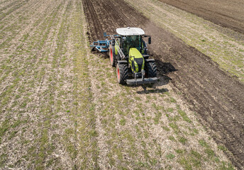 Luftaufnahme eines Schleppers mit einem Grubber bei der Arbeit auf dem Feld.