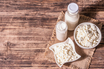 Cottage cheese in a ceramic bowl with milk in bottles