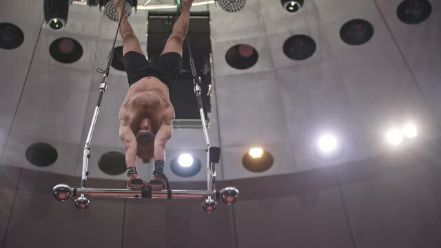 Acrobatic bearded man standing on hands upside down on performance construction 