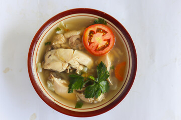 "
Chicken soup served with vegetables, tomatoes, celery in a bowl, spoon and fork. with white background"
