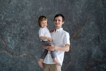 Young father holding his little son in his arms. Studio portrait