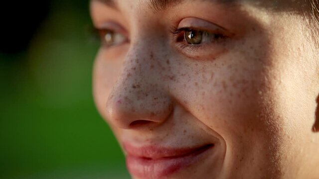 Eyes of wonderful young woman with nice Freckles opening and looking straight. Gorgeous girl with long Eyelashes. Close up of woman's face at sunset, beautiful green eyes, portrait, outdoor