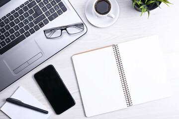 Top view of office work space, wooden desk table with laptop notebook,keyboard ,pen,eyeglasses,phone,notebook and cup of coffee.With copy space, flat lay.Mock up.