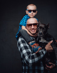 Smiling father hugging dog and his small son