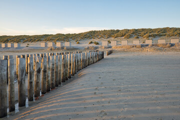 Horizontaal zicht op een strand met een rij stapelkoppen en strandcabines bij zonsondergang in de zomer. Noordzeestrand met duinen in Zeeland op een zonnige dag. Ruimte kopiëren