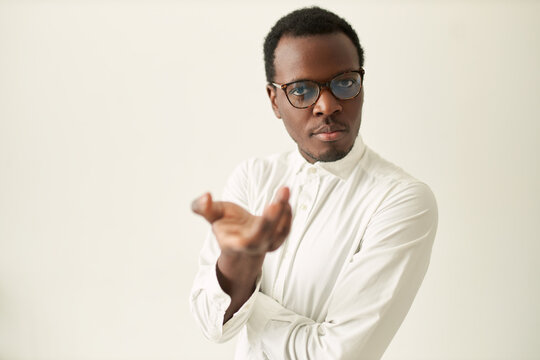 Isolated image of serious experienced young Afro American human resources manager in glasses and shirt making gesture with hand asking question during job interview, looking at camera