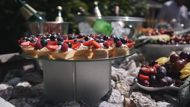Buffet table at a summer holiday event. Cool drinks, fruits and dessert baskets on the buffet table at the festive event.