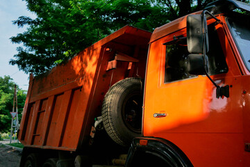 A big orange construction truck in the sunlight. Construction equipment on road work in the city.