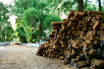 A large pile of wooden sleepers in the daylight. A row of wooden bars lies on top of each other. Replacement of old streetcar sleepers in the city.