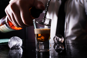 Barman preparing cocktail shots at the bar counter. Barman mixing drinks at the night club