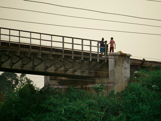 Kids wondering upon railway bridge from wide angle photograph.