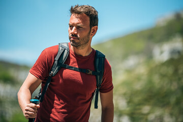 Male hiker walking with trekking poles in mountainous terrain