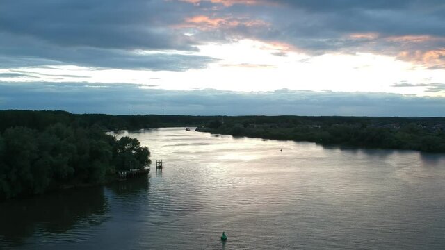 Colorful clouds and vast river Schelde in aerial descend view