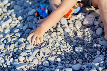 A child plays with toys and pebbles on the beach. The concept of recreation, play and the development of children's motor skills