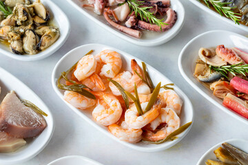 Set of Seafood Dishes. Seafood on a plate. On a white wooden background. Selective focus Shrimp. Prawns, lakerda, octopus salad, mussels with marinade